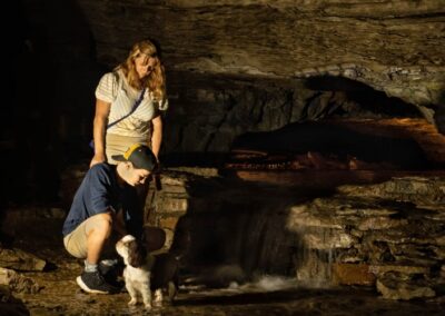 Mother, son, and dog by a waterfall in the cavern